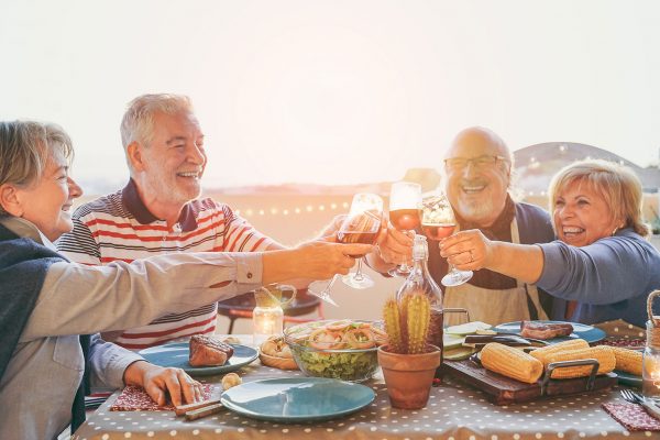 two older couples cheering their glasses together