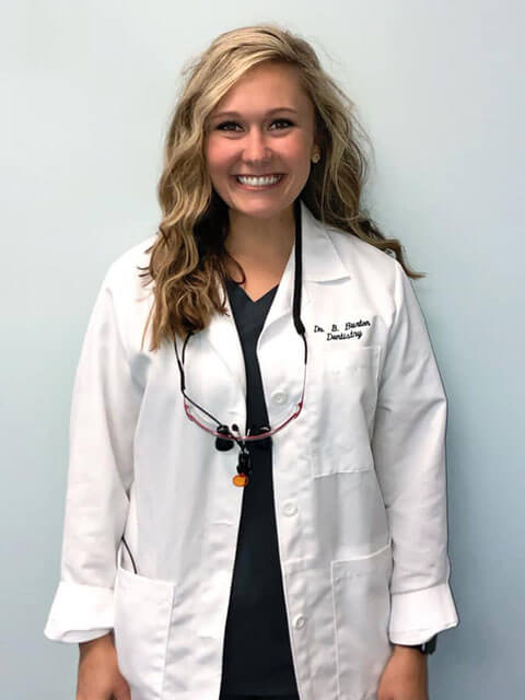 smiling blonde woman wearing dentist coat