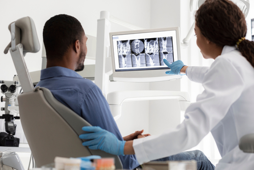 female dentist and male patient looking at digital x-rays